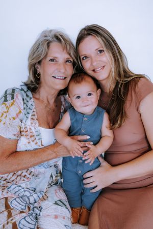 Multi-generational family portrait with matching outfits in a bright studio setting.