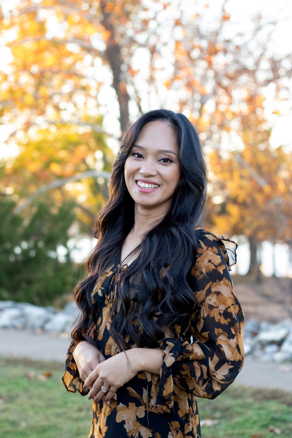 Woman looking at the camera and smiling in by the lake.