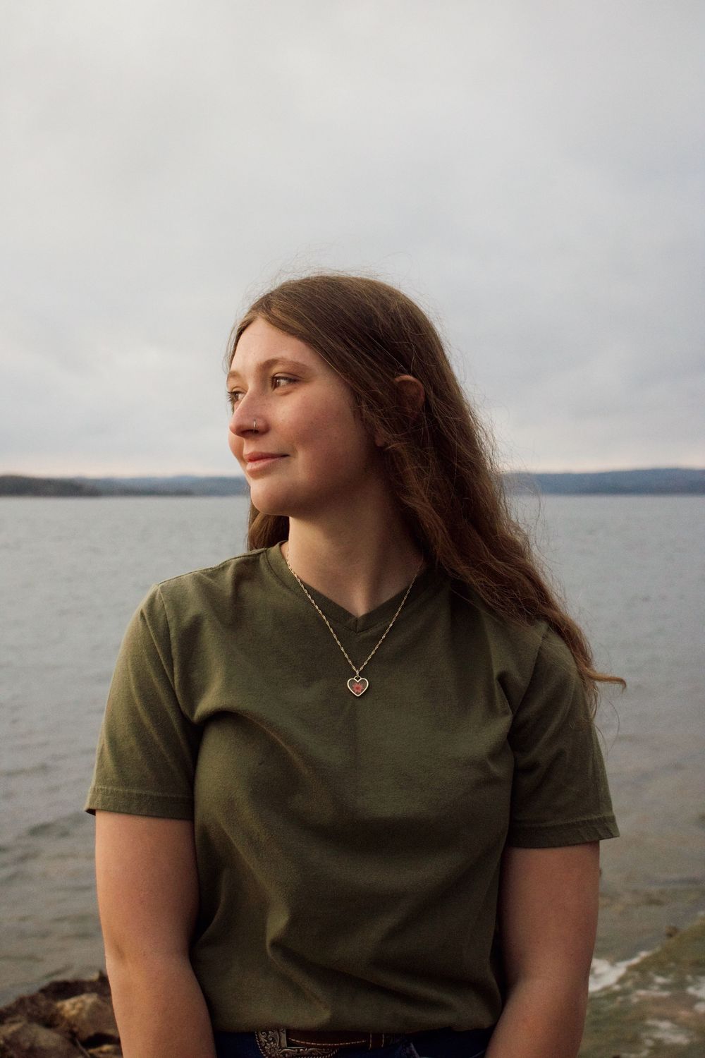Girl smiling looking off to the distance in front of the lake for her senior pictures.