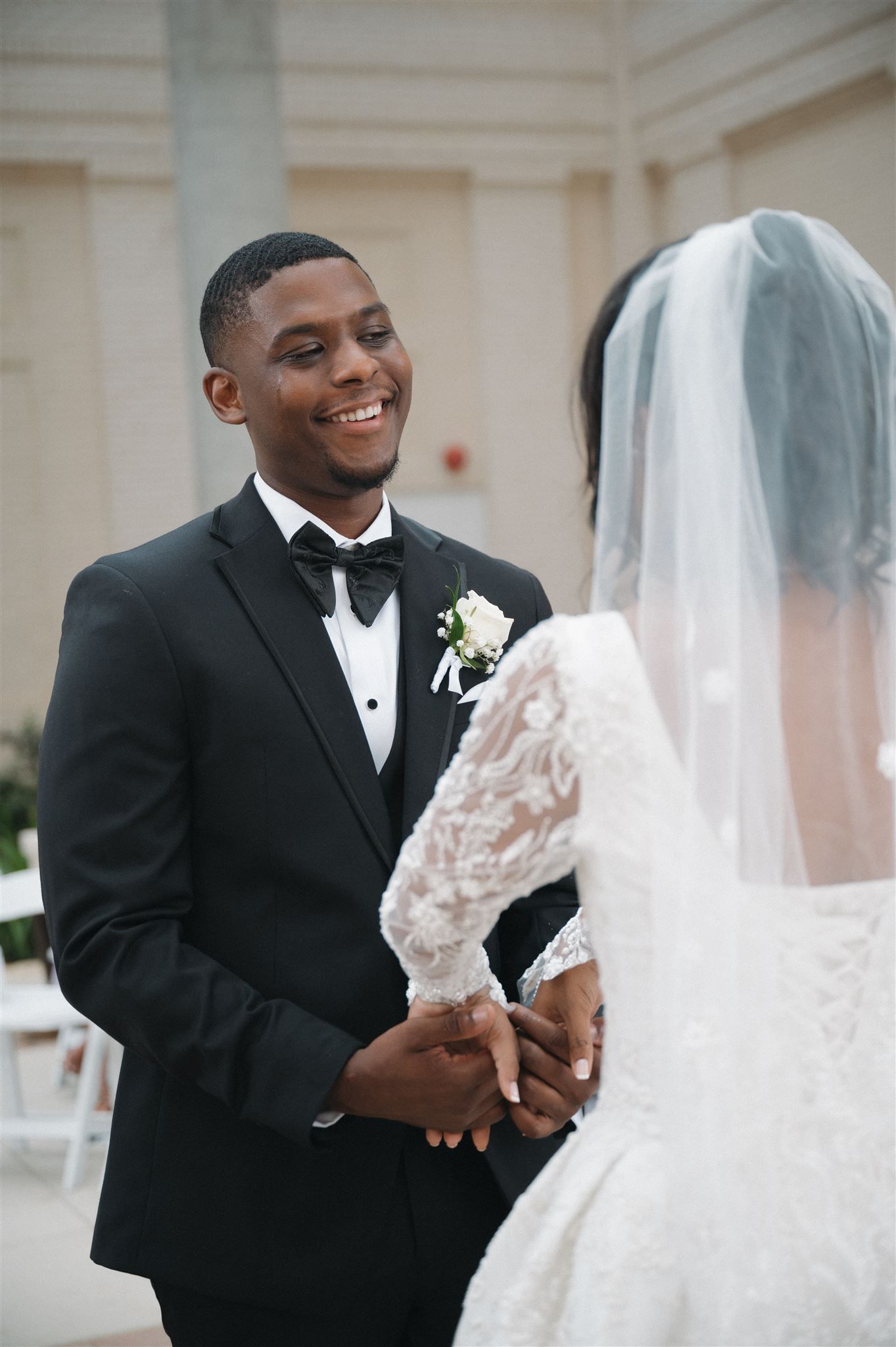 Beautiful wedding moment captured showing a joyful exchange between newlyweds, with the bride in lace and groom in classic tuxedo.