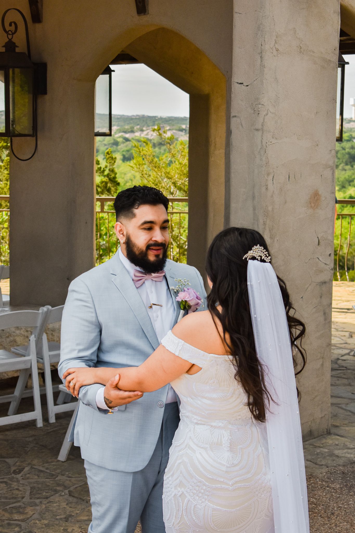 Wedding couple sharing a moment under a Mediterranean-style archway with outdoor views.
