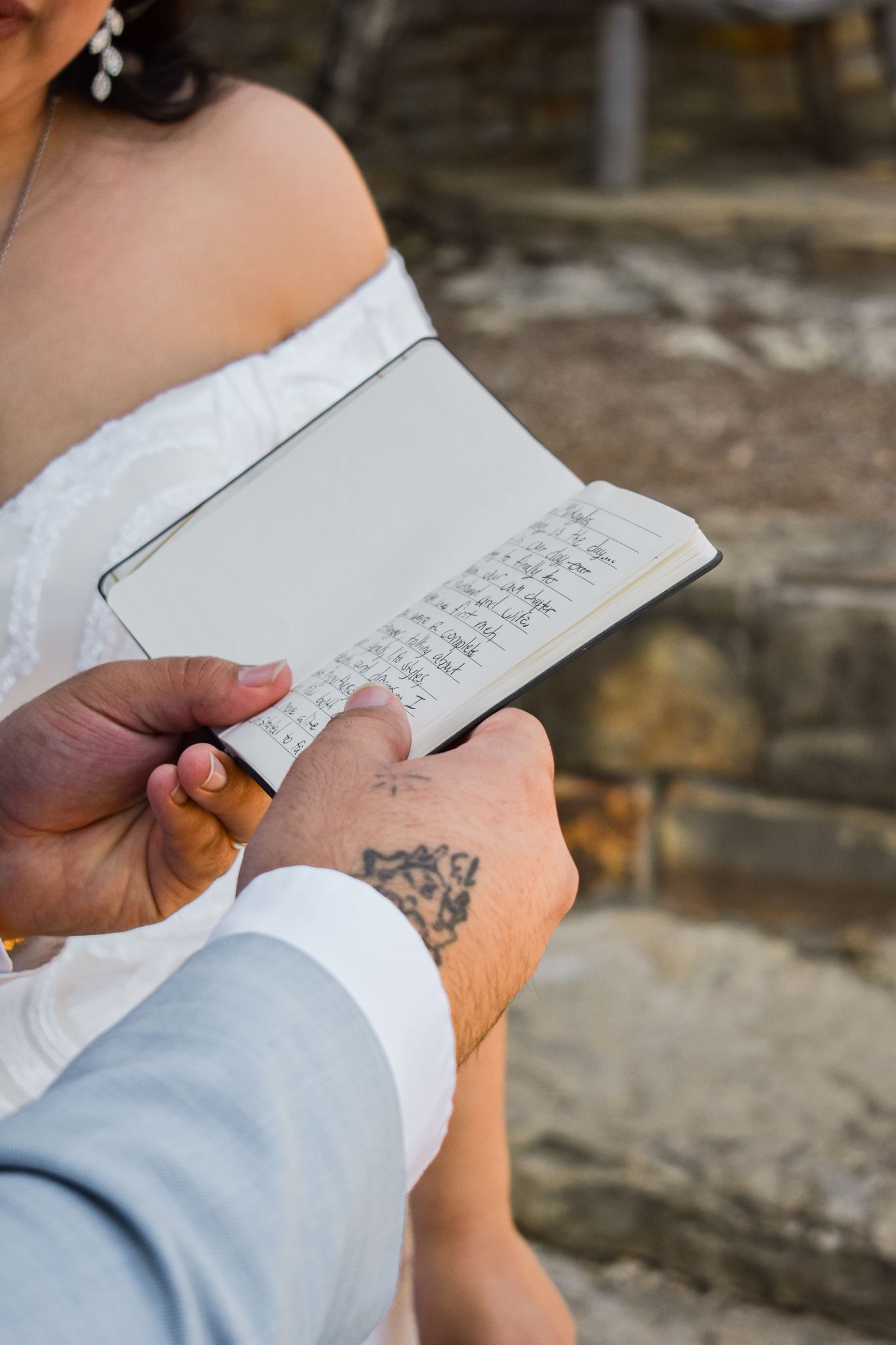 Person in light blue suit writing in a small notebook during wedding ceremony.