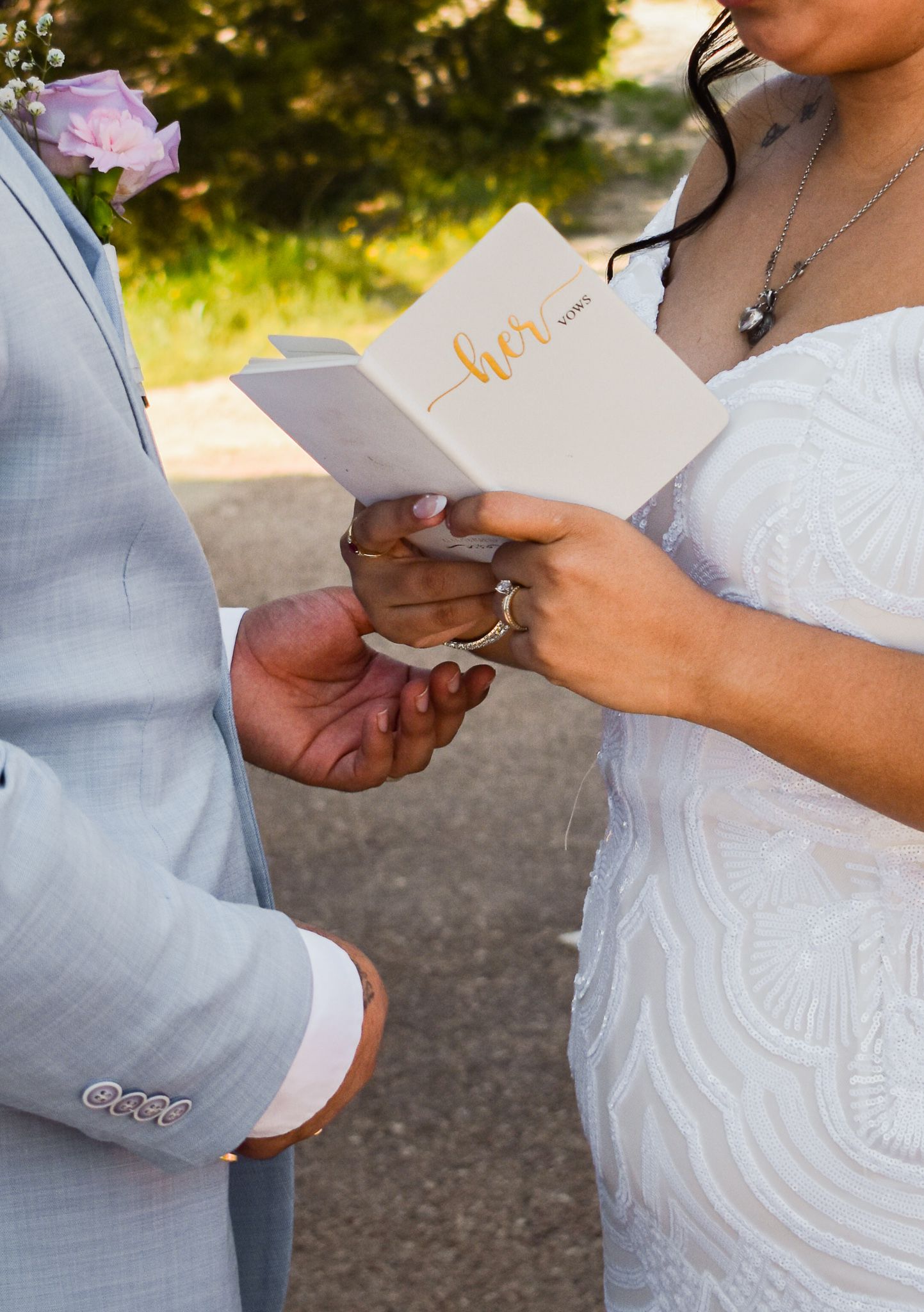 Couple exchanging vows or reading from cards during outdoor wedding ceremony.