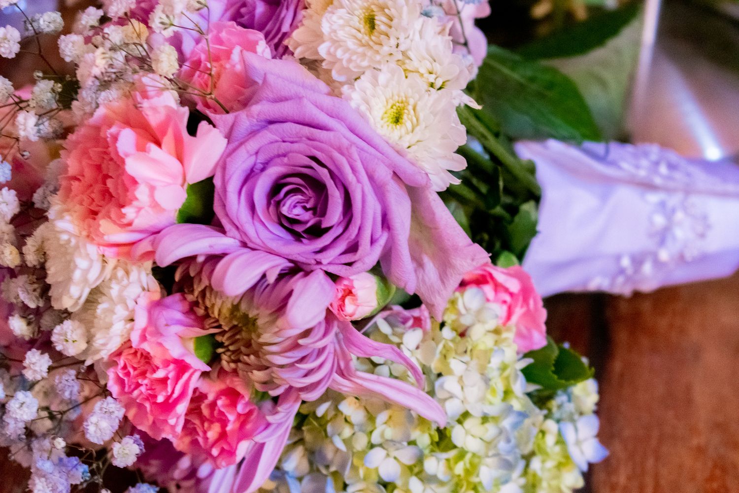 Close up of pink and purple rose wedding bouquet with baby's breath accents.