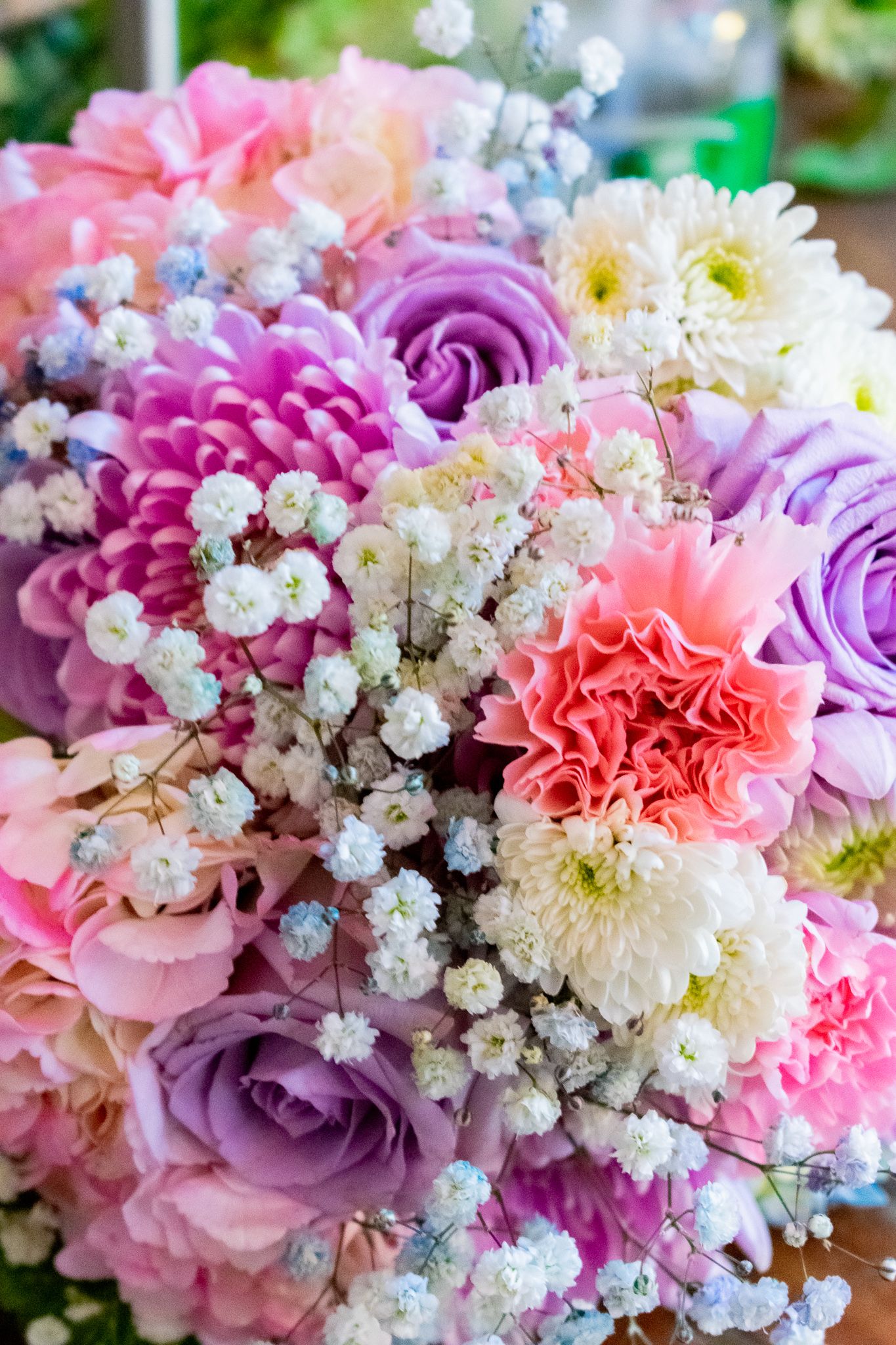 Colorful wedding bouquet with pink and purple roses, carnations and baby's breath flowers.