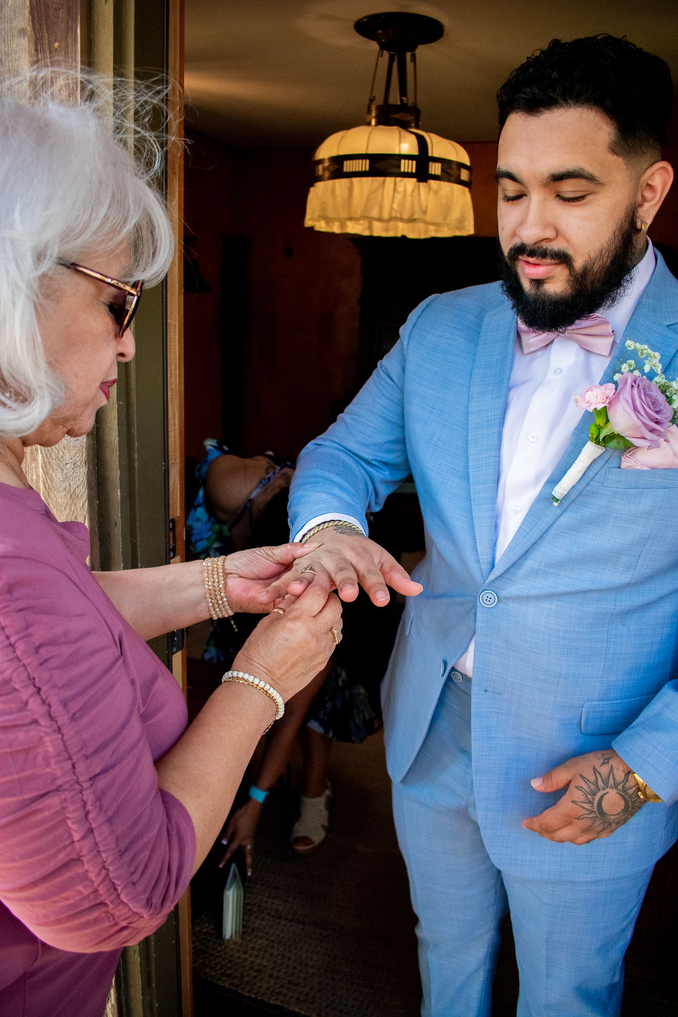 Wedding preparation moment showing groom in light blue suit getting ready.