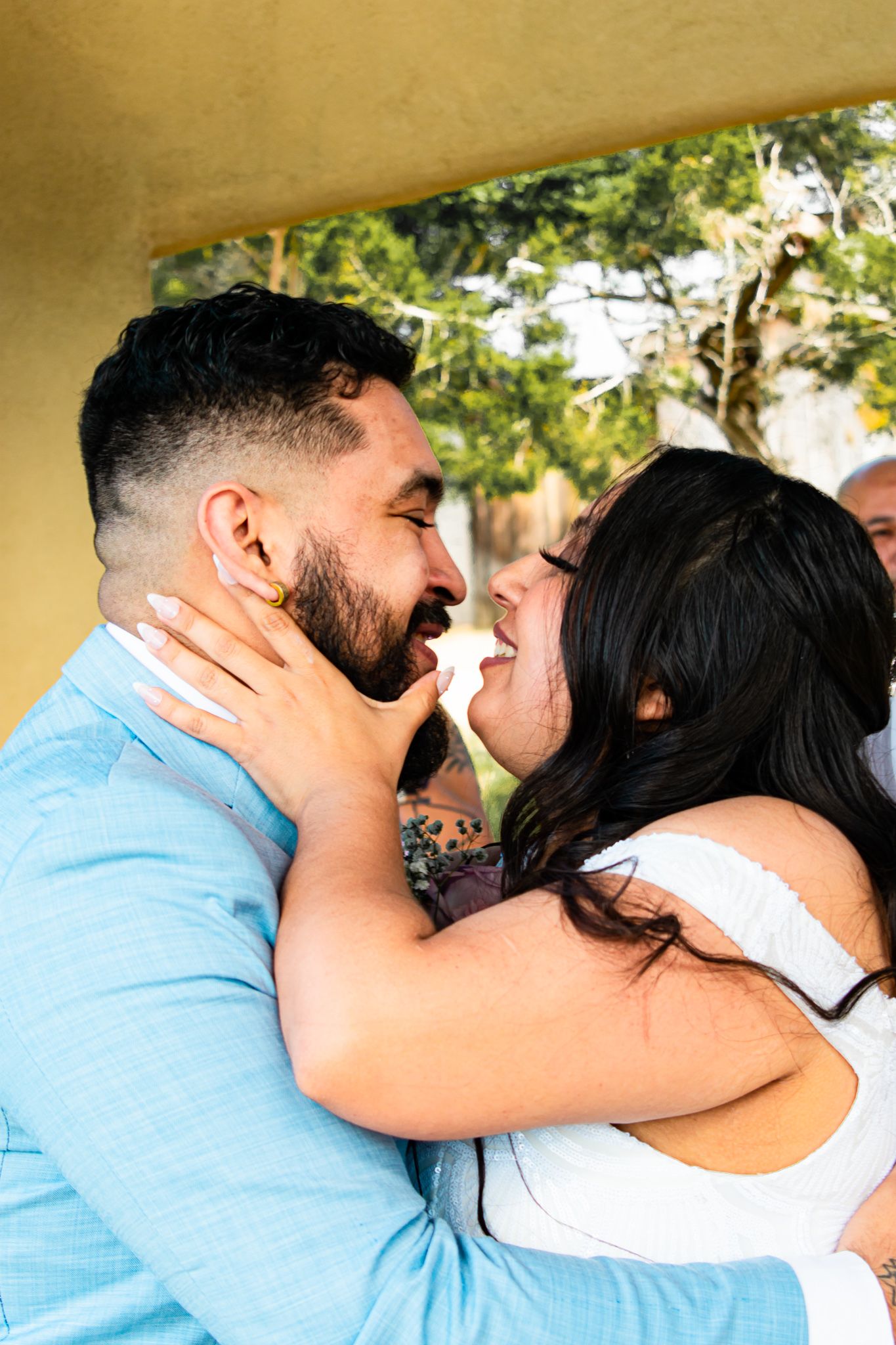 A couple in blue and white outfits share an intimate moment outdoors.