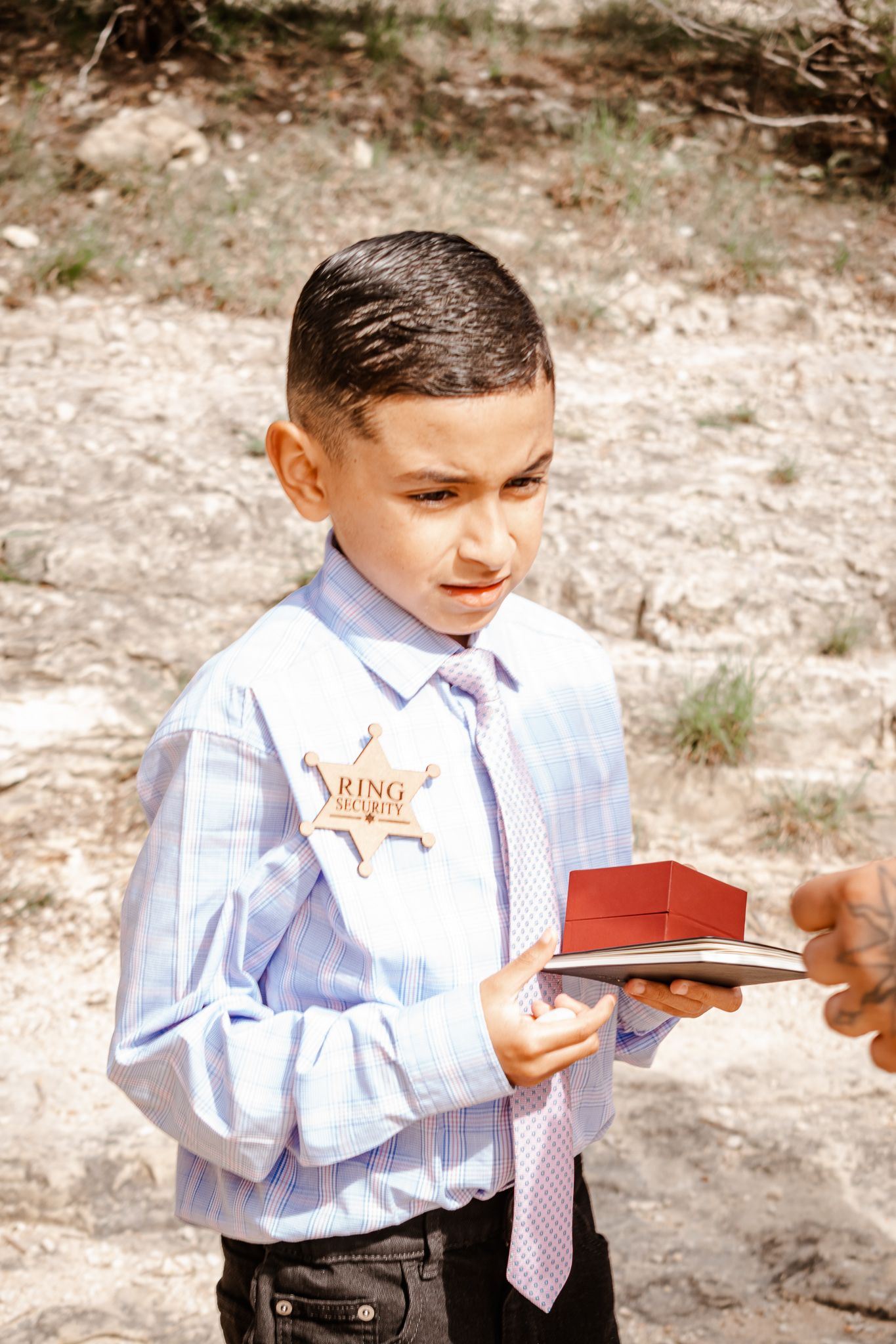 Young ring bearer in formal attire holding a decorative wooden box.
