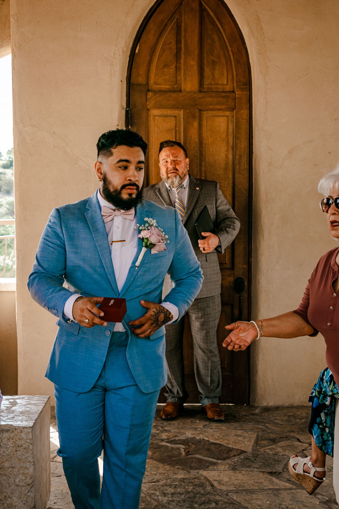 A formal gathering outside a chapel entrance with arched wooden doors.