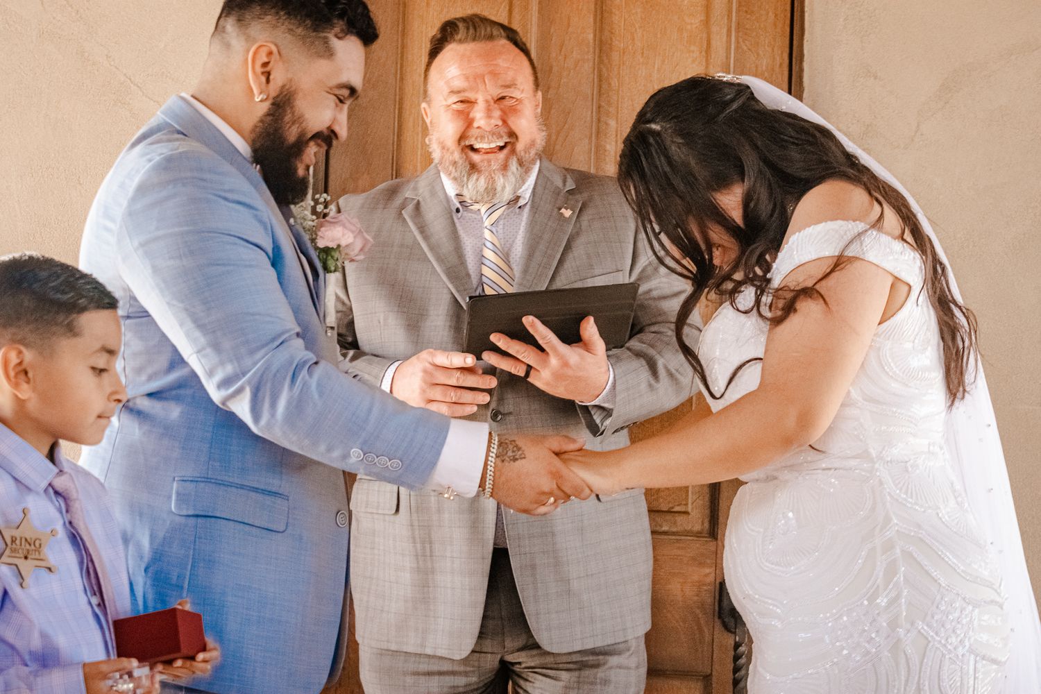 A small wedding ceremony with participants sharing a joyful moment during the ring exchange.