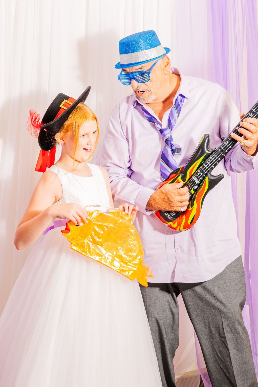 Photo booth participants pose with props including a toy guitar and festive accessories.