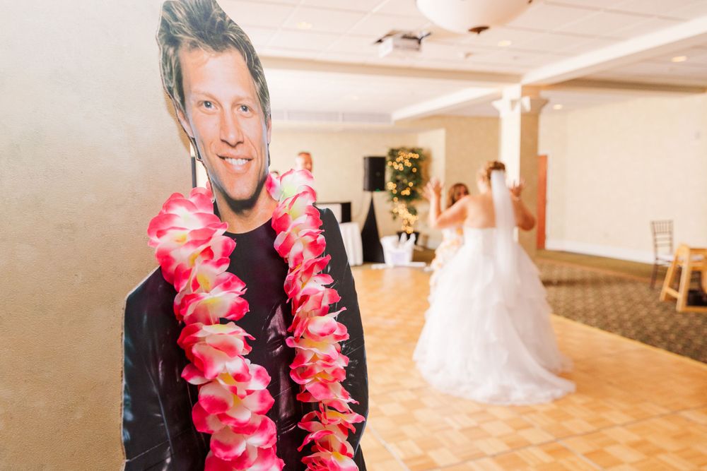 A cardboard cutout with a lei stands in front of a wedding reception scene.