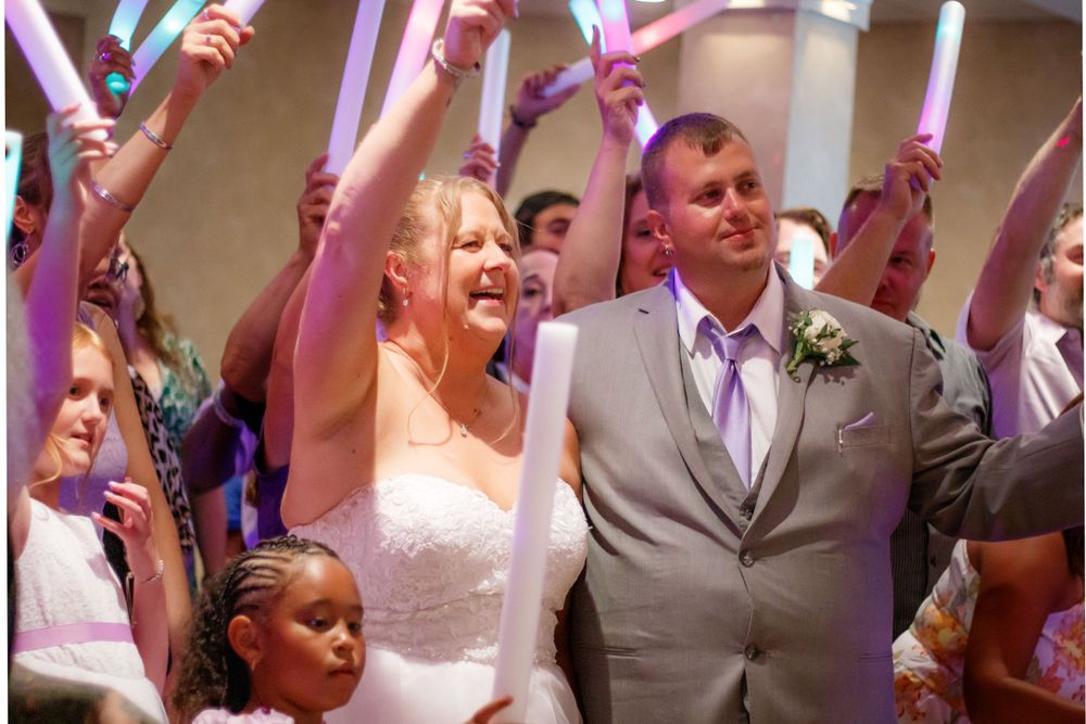 Wedding celebration with guests waving light-up foam sticks during reception party.
