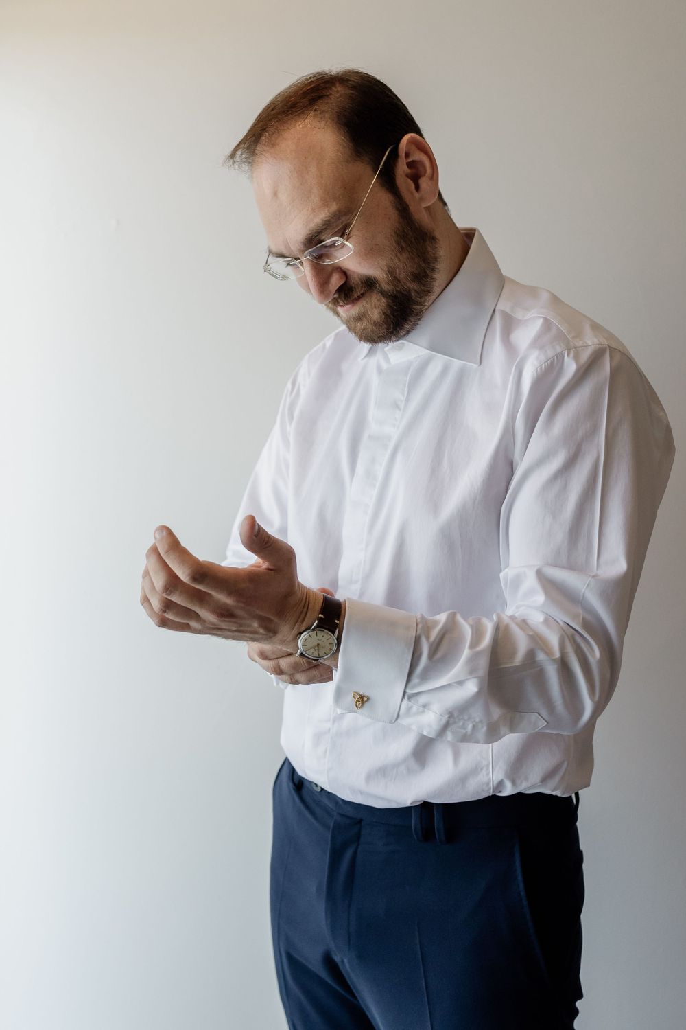 A person in white dress shirt adjusting cufflinks while getting ready.