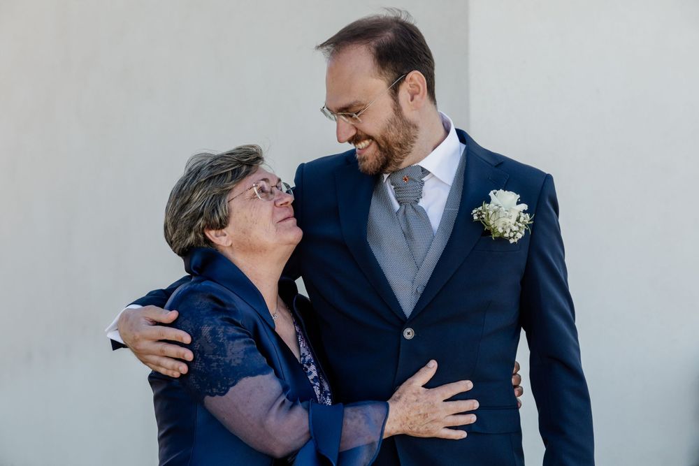 Sweet moment shared between wedding guest in navy dress and suited attendee with boutonniere.