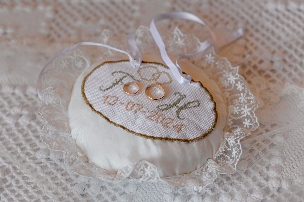 White lace ring pillow with embroidered wedding date in gold thread.