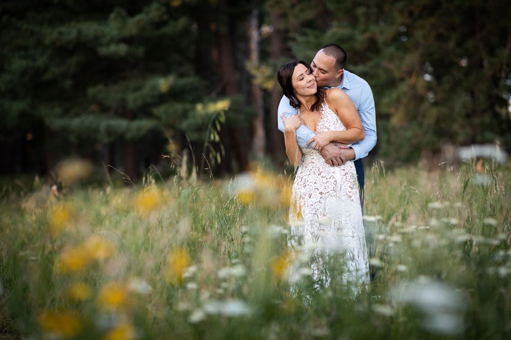 Romantic couple embraces in wildflower meadow during golden hour.