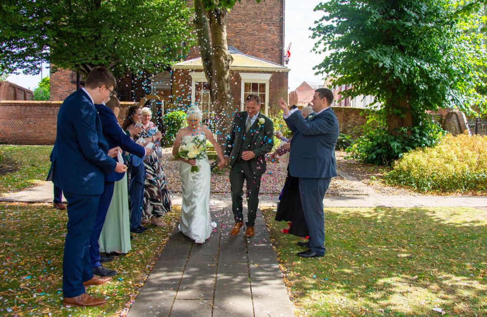 Small wedding ceremony taking place outdoors under green trees.