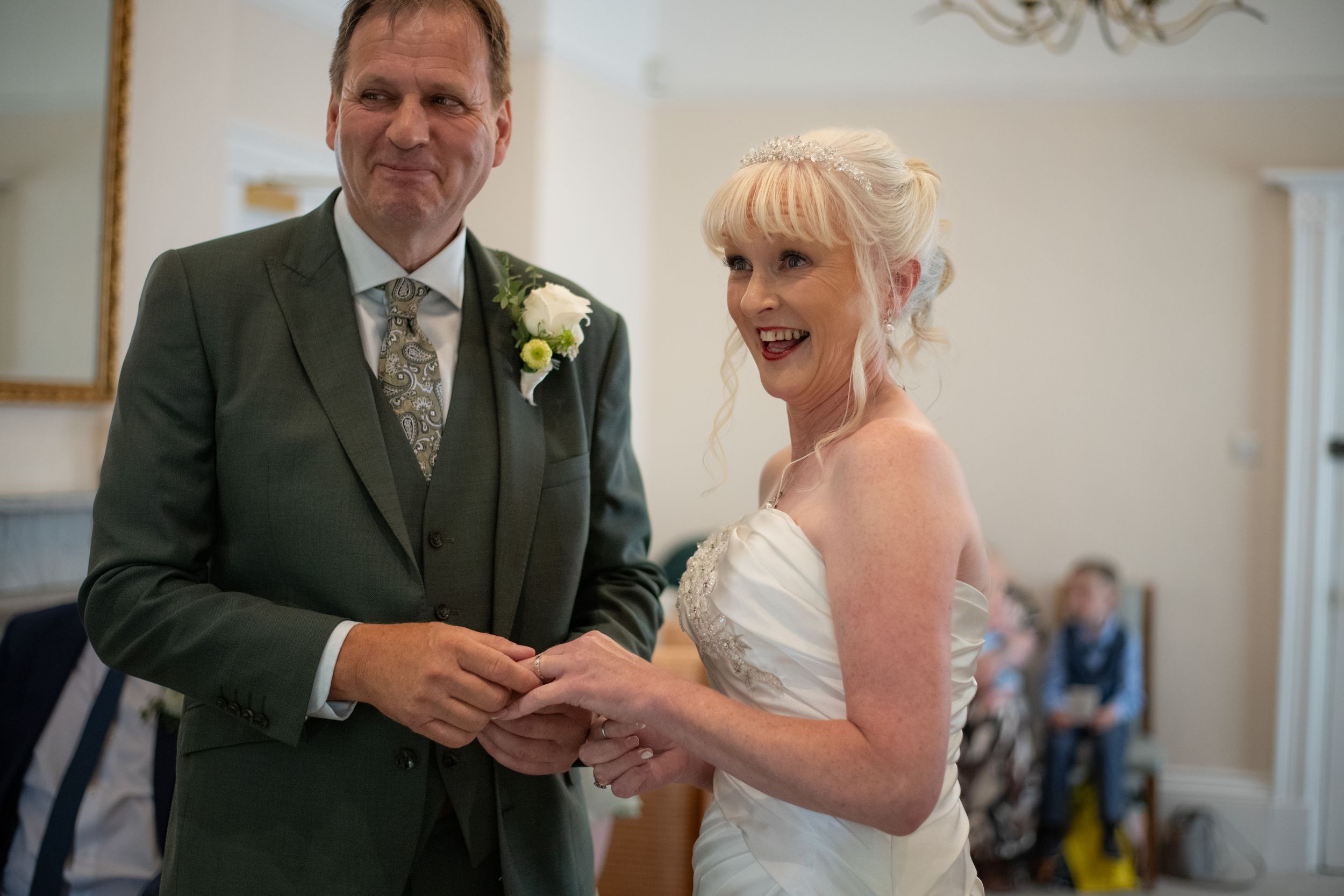 Joyful moment during ring exchange at indoor wedding ceremony.