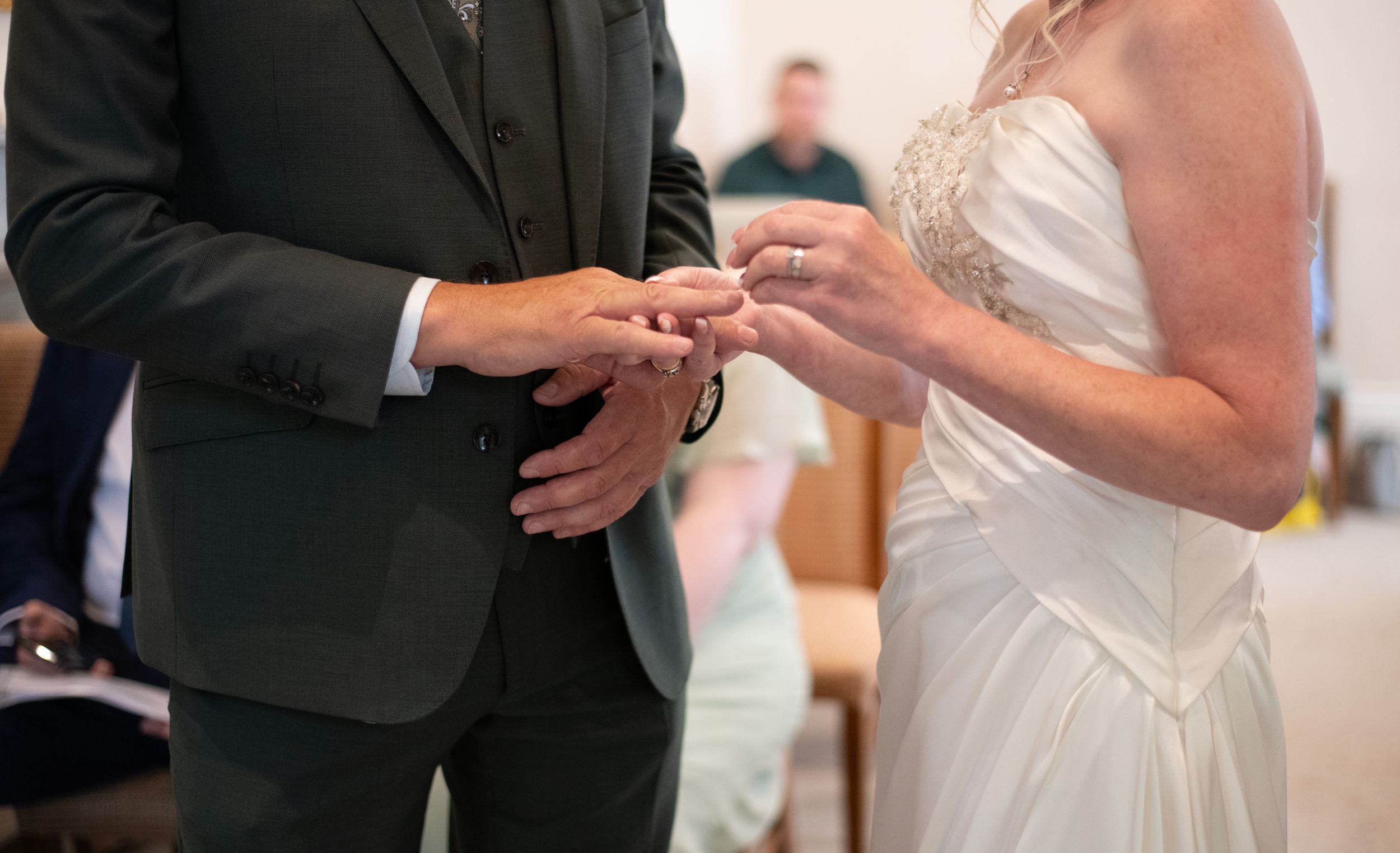 Close-up of hands exchanging wedding rings during ceremony.