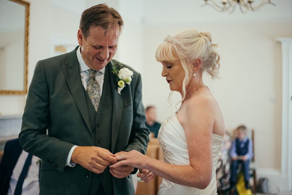 Emotional exchange of rings during indoor wedding ceremony.