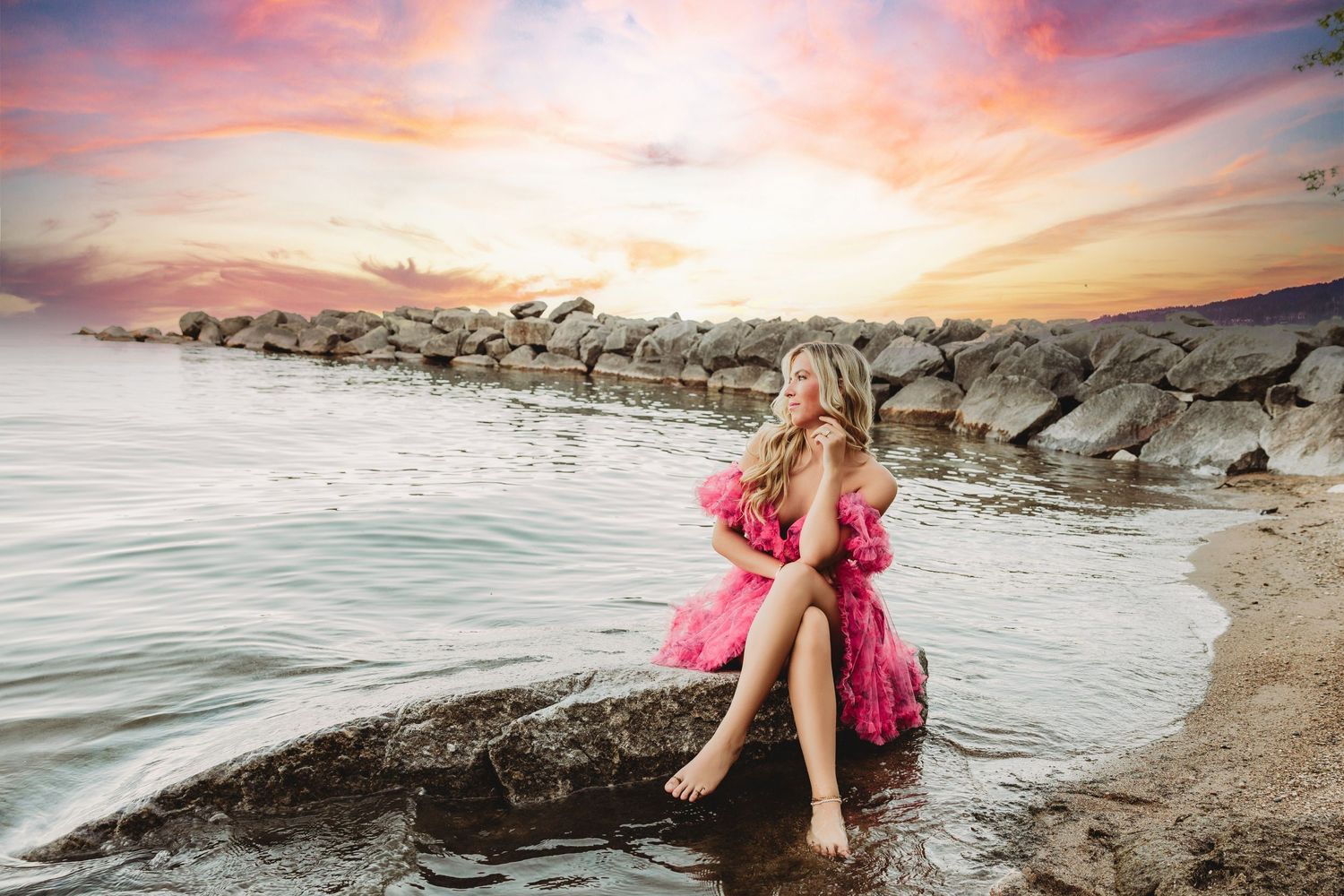 Scenic beach photoshoot at sunset with pink dress and coastal rocks in the background.