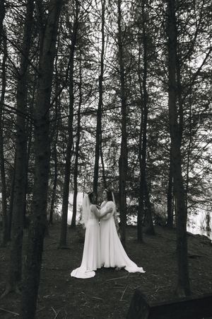 Ethereal white dress floating among dark forest trees in black and white photography.