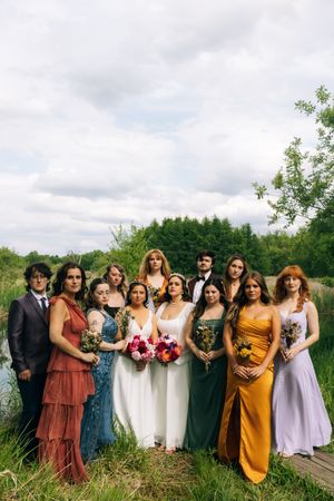 Wedding party in colorful dresses posing together in a natural outdoor setting.