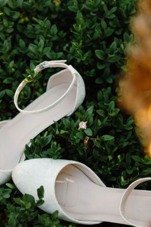 White bridal shoe displayed against green foliage background.