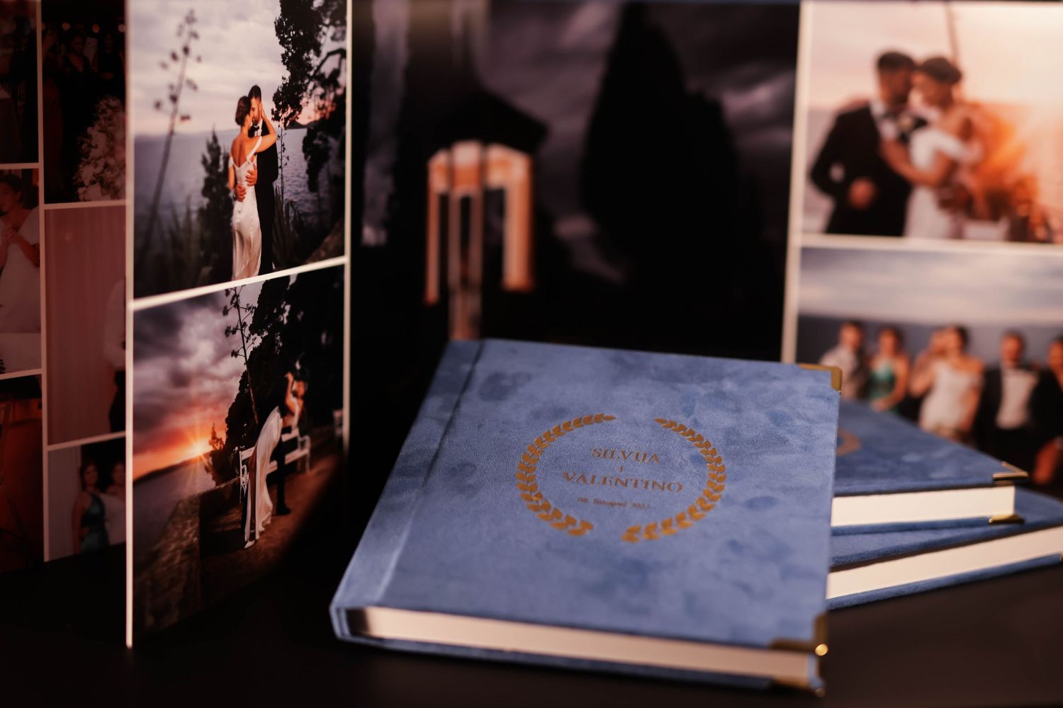 Wedding photo display featuring blue album with gold accents alongside mounted photographs.