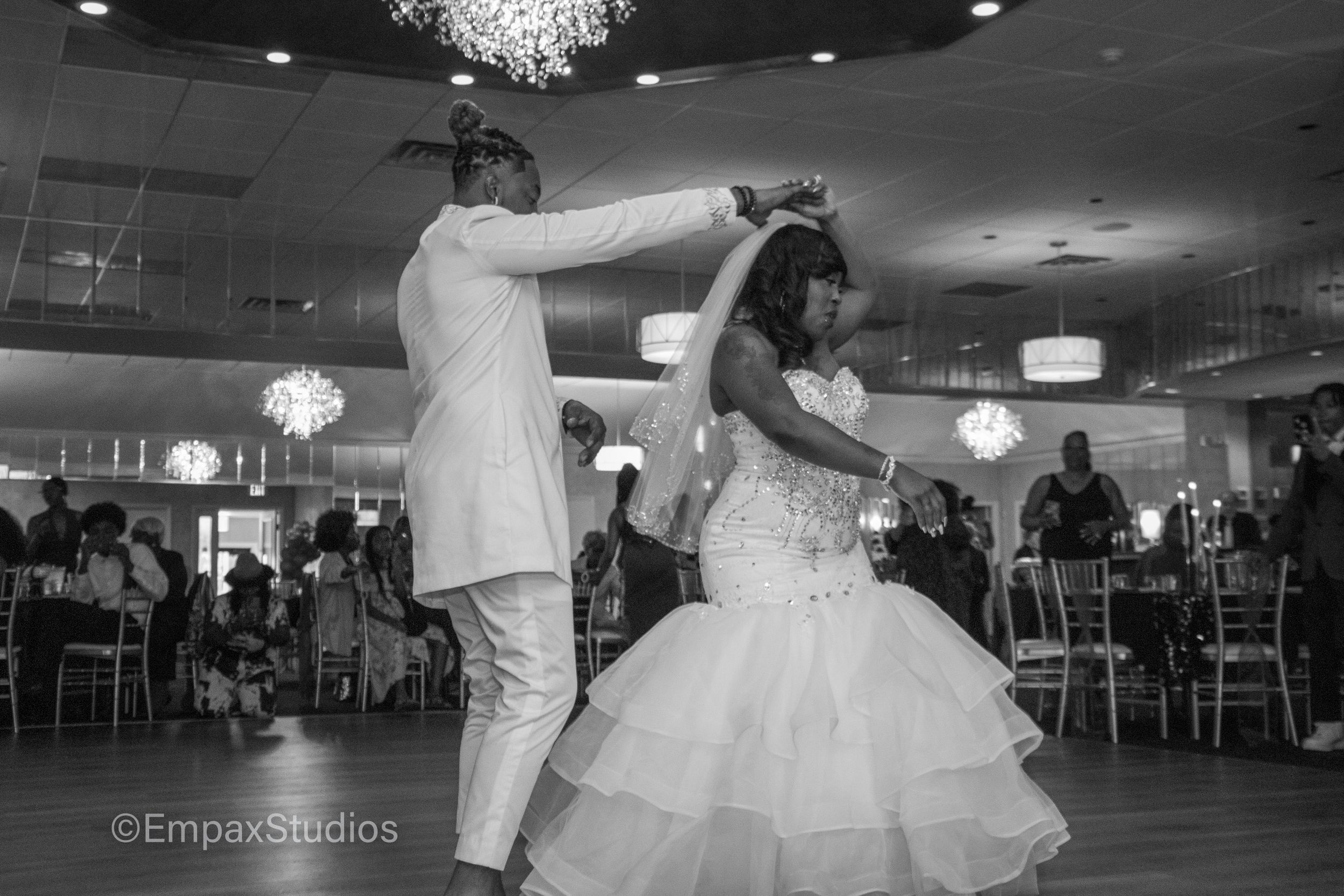 A black-and-white photo of a newlywed couple dancing together during their wedding reception.