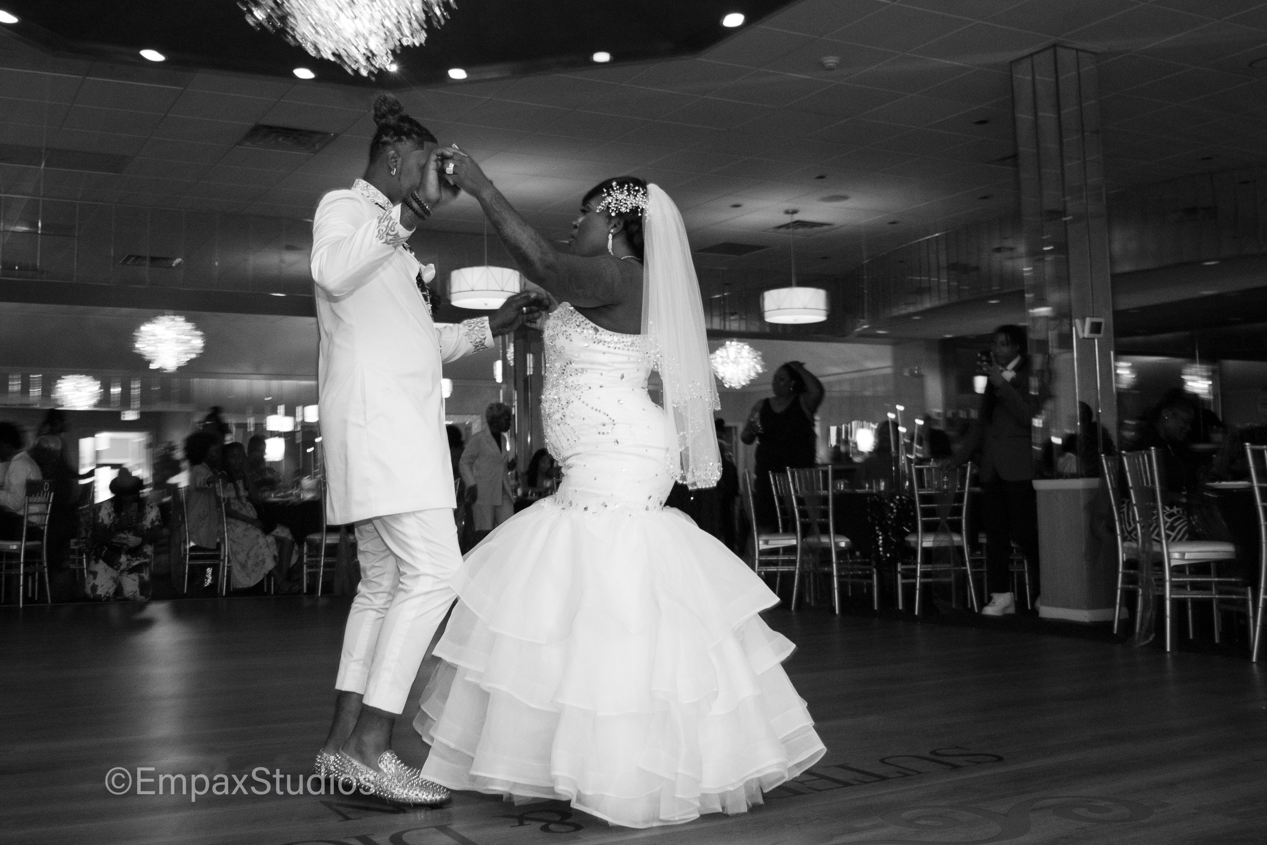 A black-and-white photo of a bride and groom dancing together during their wedding reception.