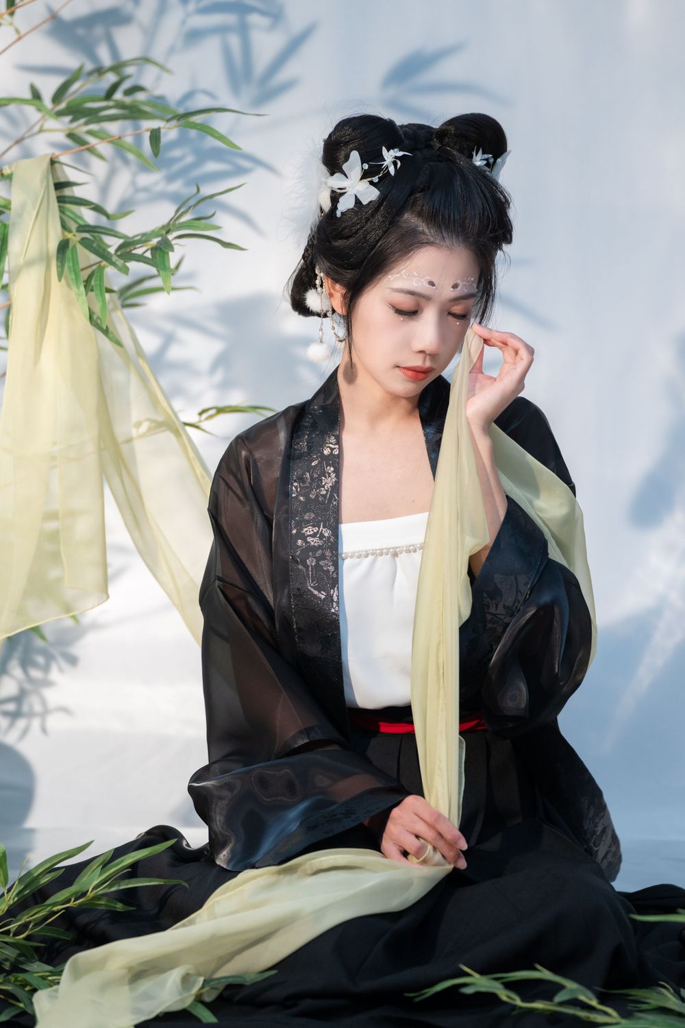 Cinematic studio photo of a young woman in black and white panda Hanfu cosplay, sitting among bamboo. She has tears streaking down her face