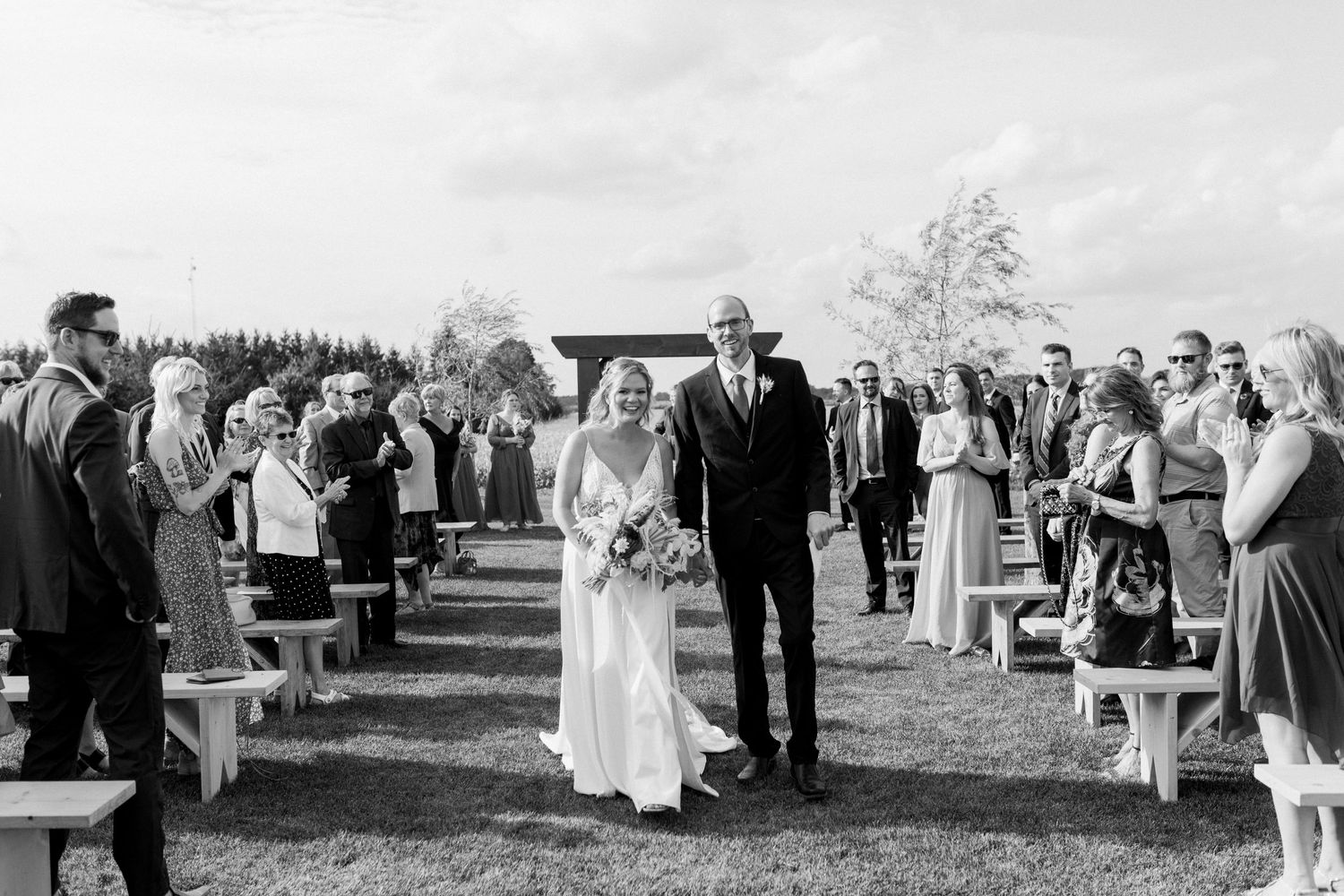 Joyful moment of bride and groom walking up the isle at Barnswallow Field in Guelph, Ontario, taken by Katie Crane.