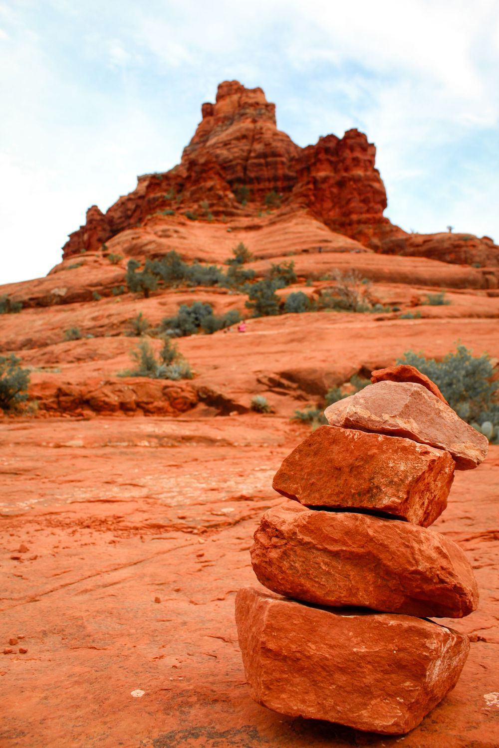 Stacked red rocks cairn with Bell Rock butte formation in background at Sedona Arizona red rock country.