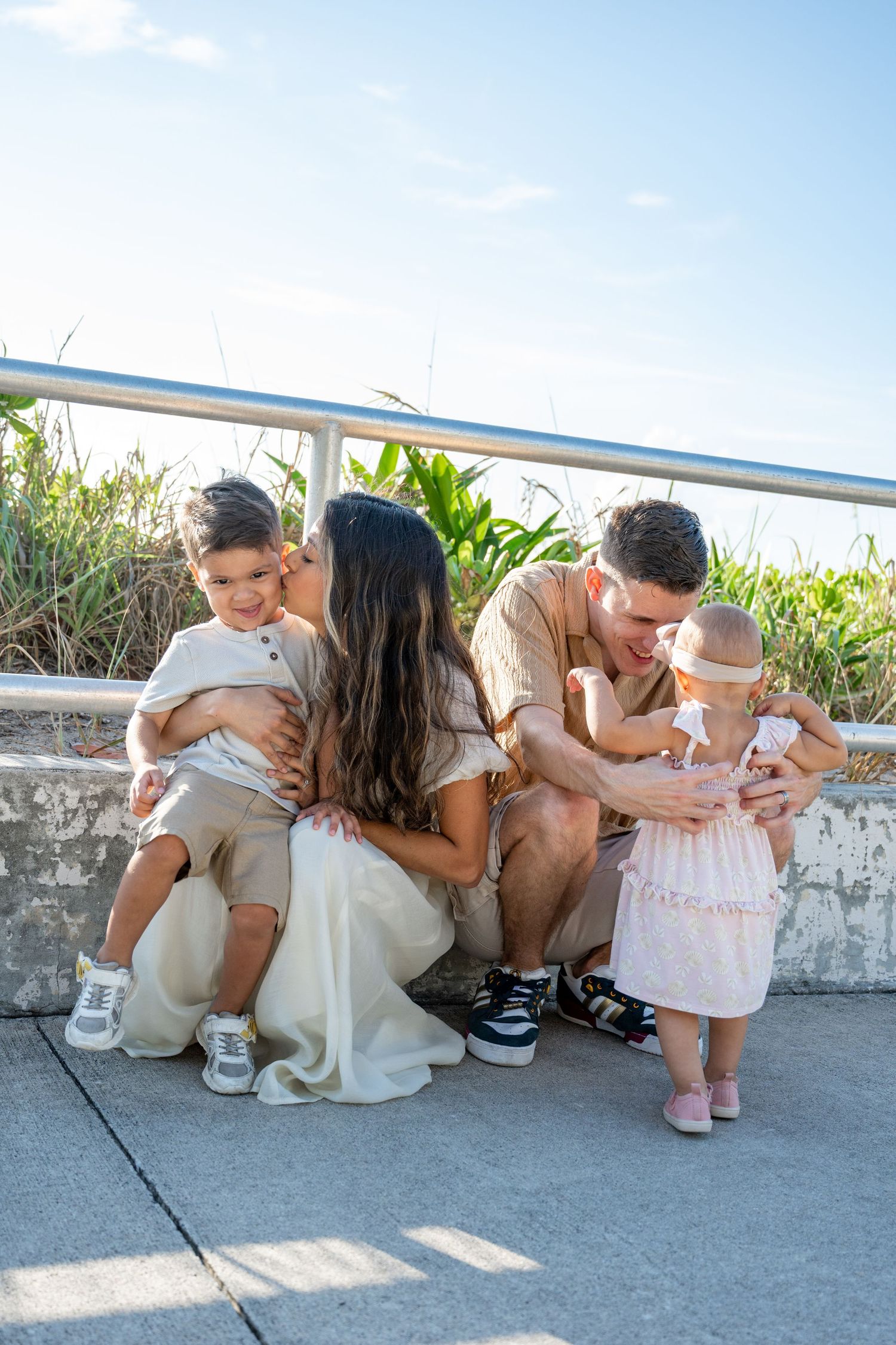 Family sitting together on concrete steps surrounded by lush greenery.