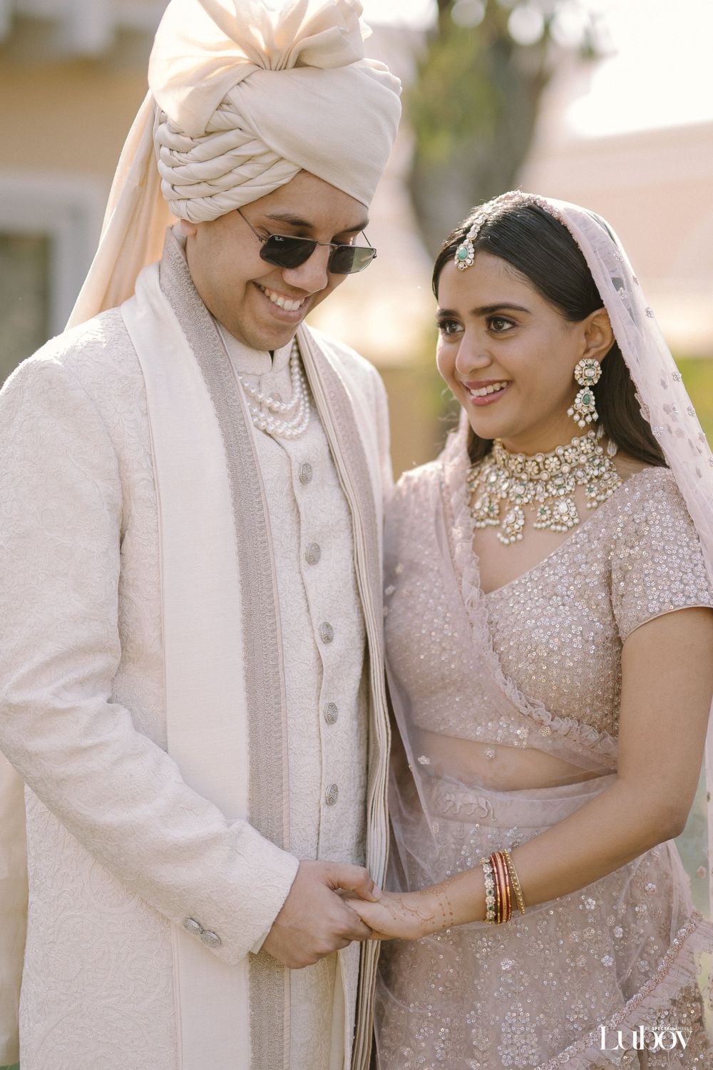 Couple in elegant cream and blush wedding attire share an intimate moment.