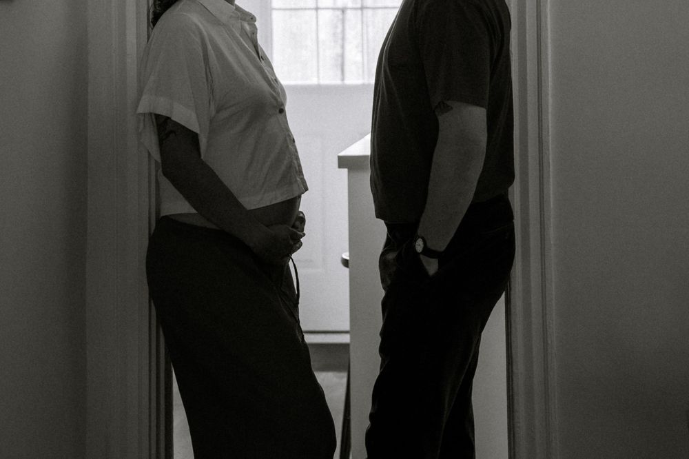 Silhouette of two people standing in a doorway against window light.