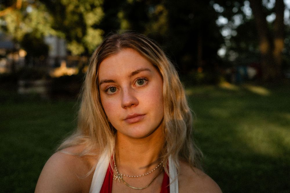 Portrait of woman during golden hour in a grassy outdoor setting.
