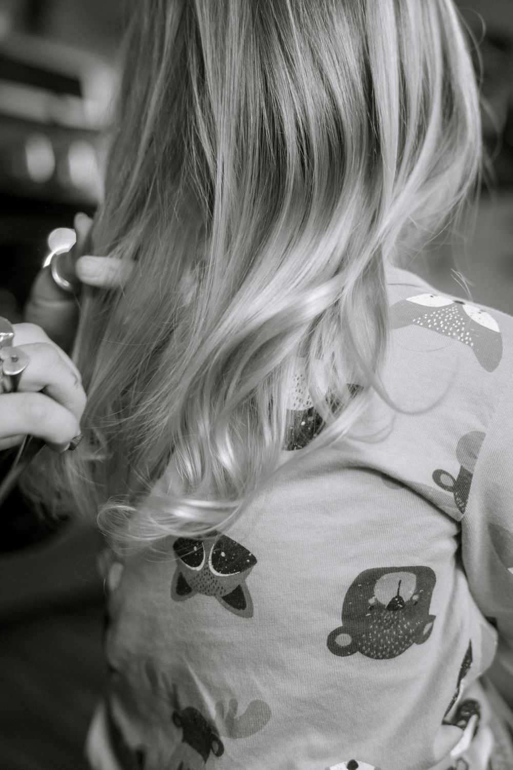 Close-up of blonde wavy hair and a shirt with cute animal patterns in black and white.