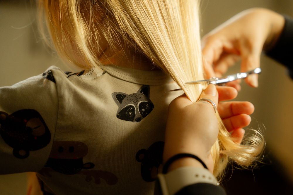 Blonde hair being tied back while wearing a shirt with woodland animal prints.