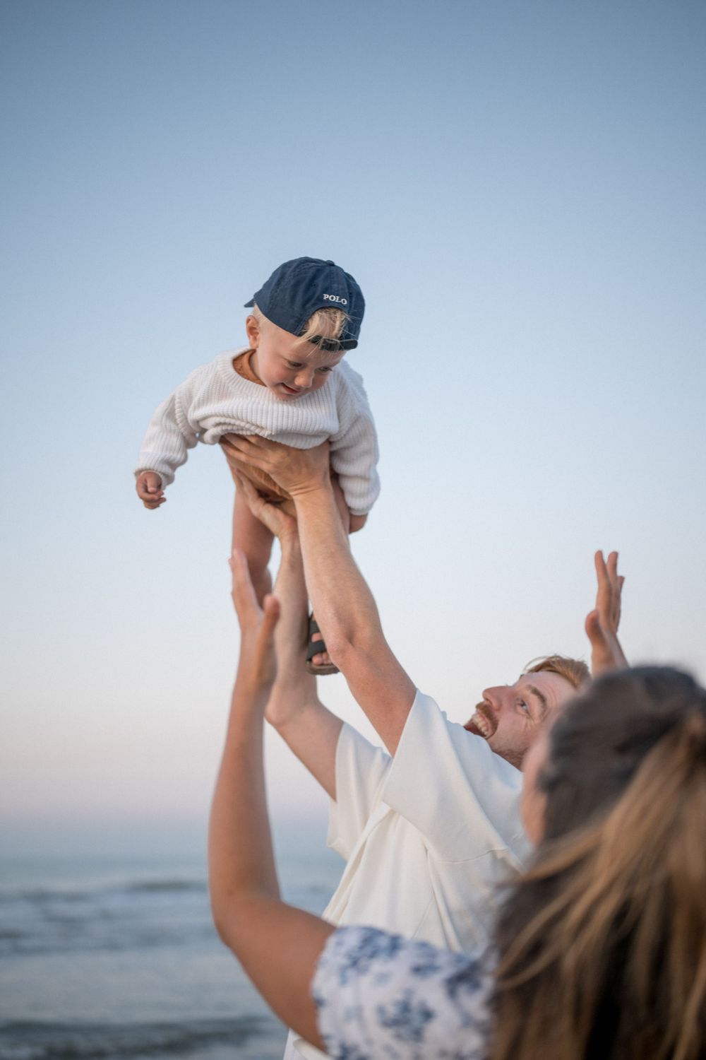 Joyful moment at the beach as small child is lifted high into the air.