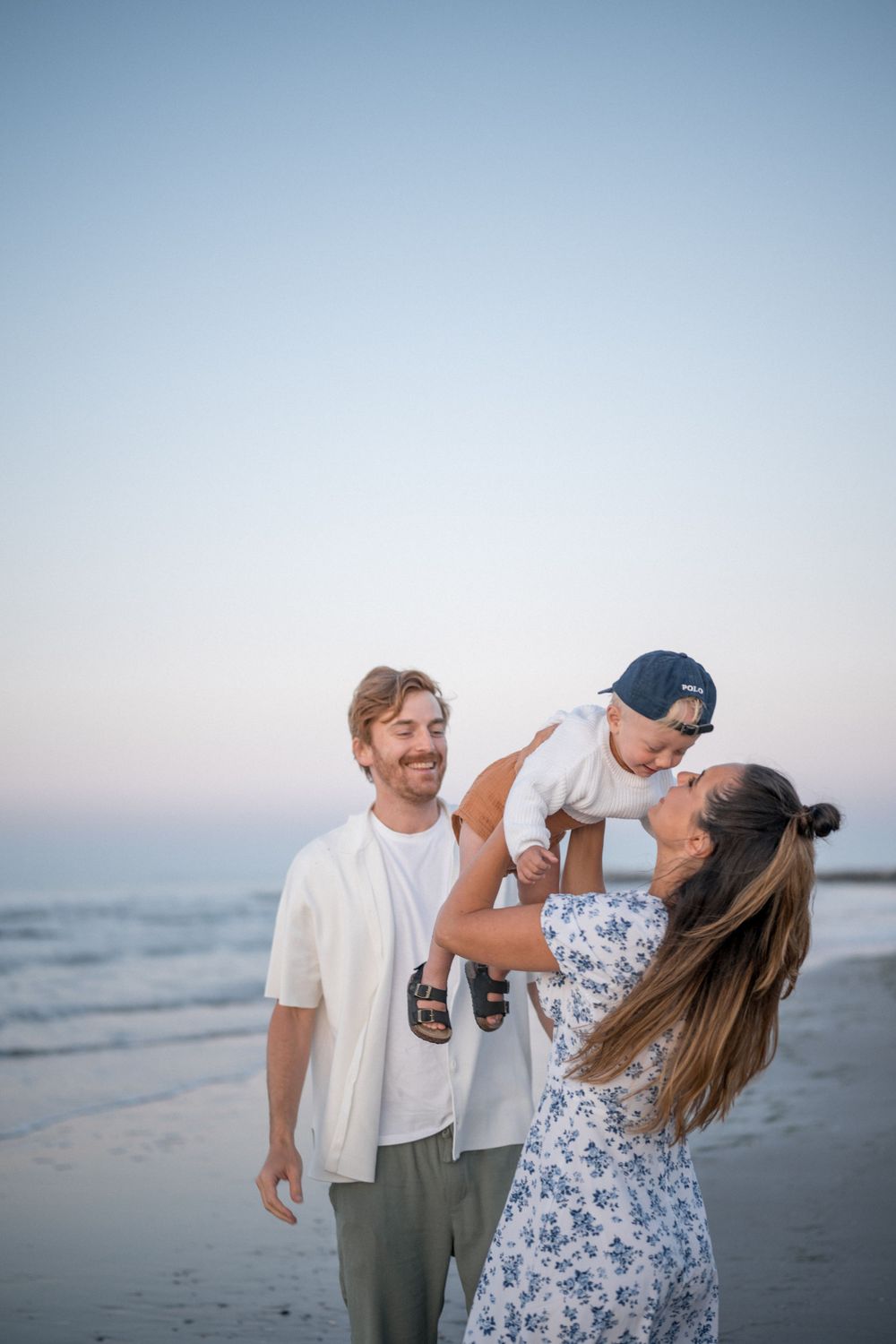 Family enjoying a playful moment together at sunset on the beach.