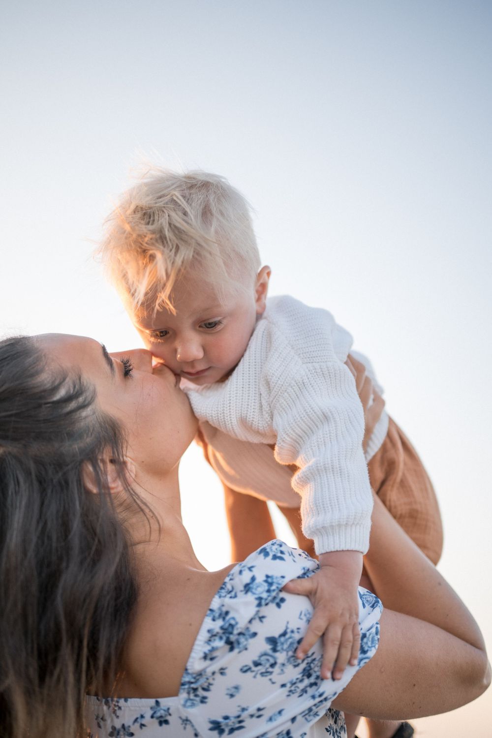 Tender moment between parent and child against a bright sky background.