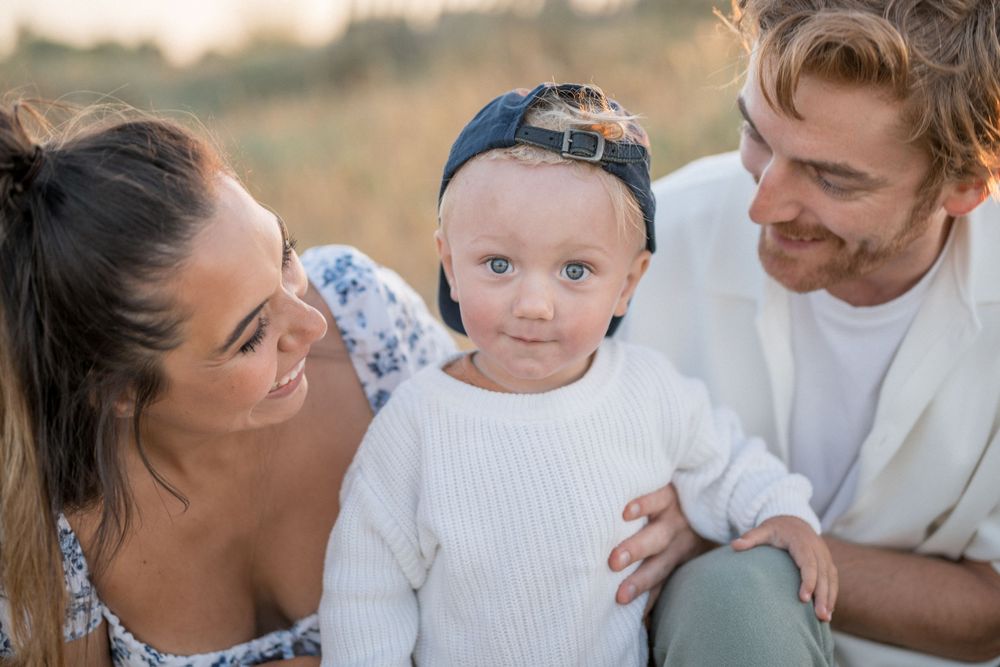 A young family shares a candid moment outdoors during golden hour.