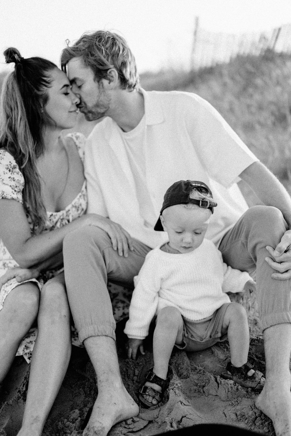 A candid family moment captured on the beach in black and white photography.
