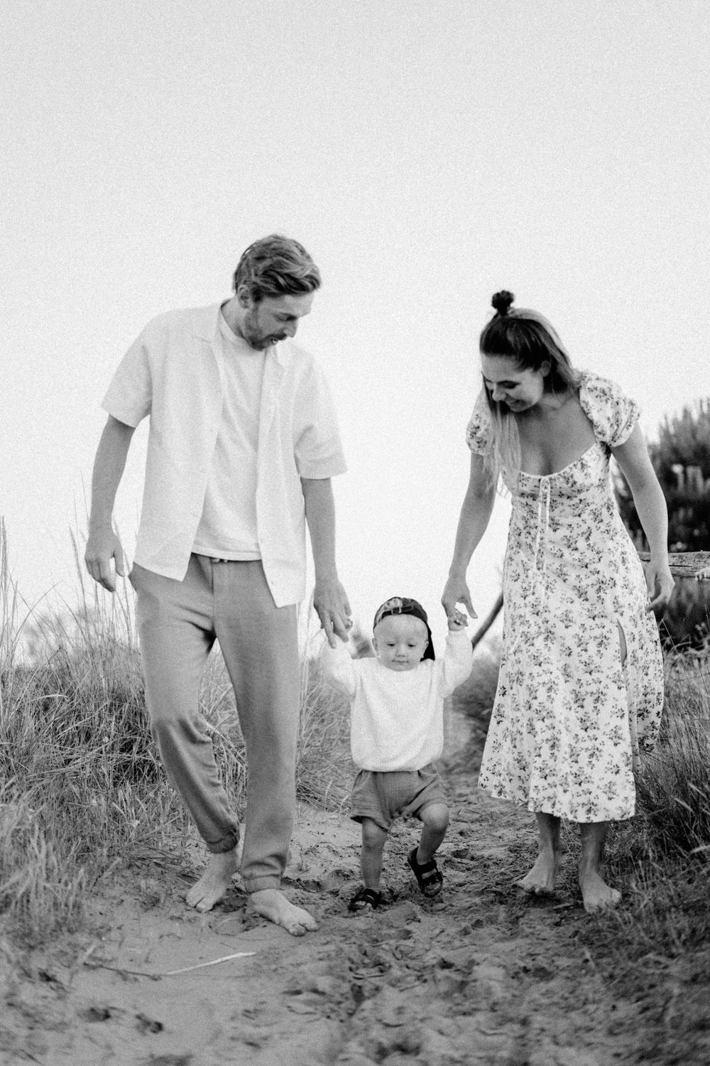A family walking together on sandy dunes in black and white.
