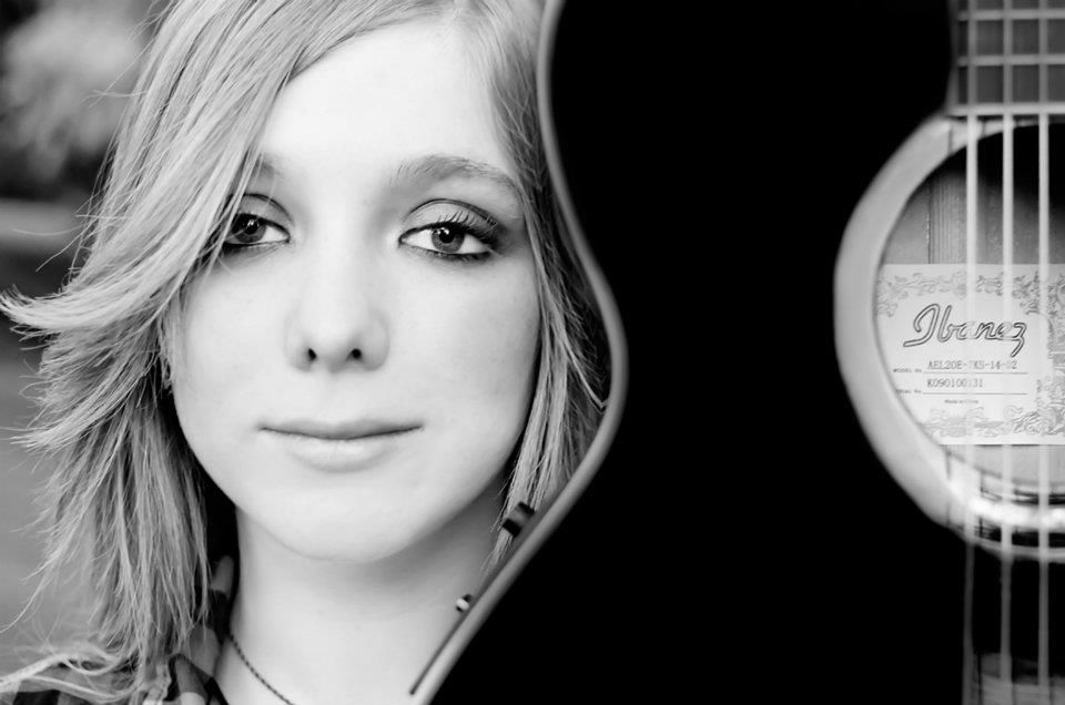 Artistic black and white portrait with acoustic guitar visible in frame.