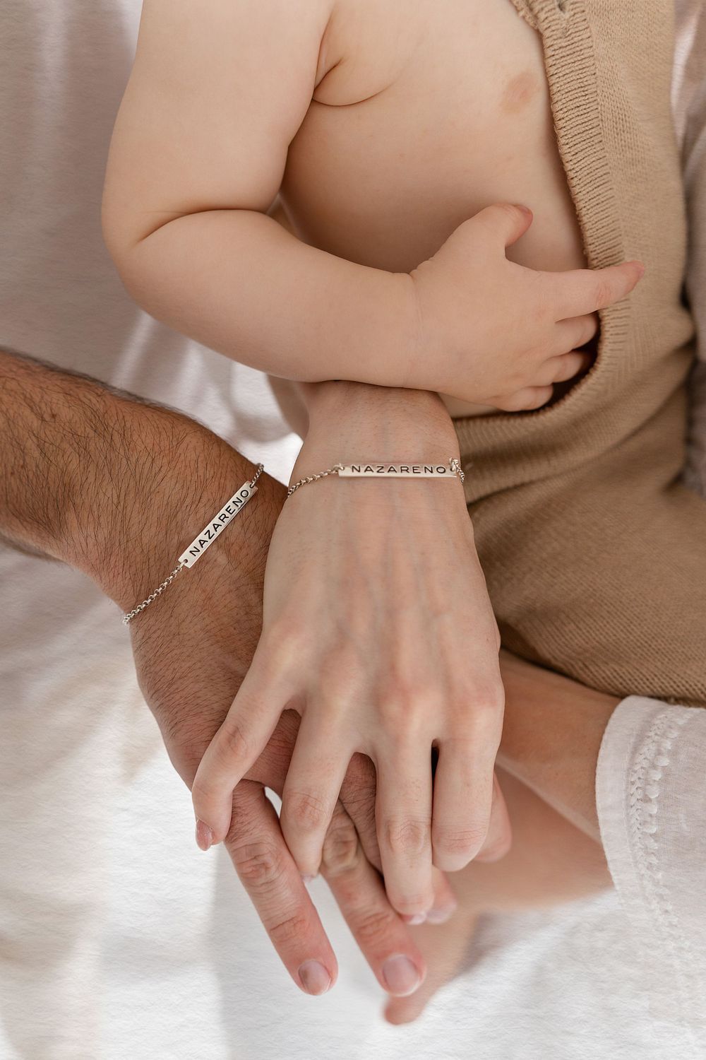 Close-up of parent and child hands wearing matching silver bracelets.