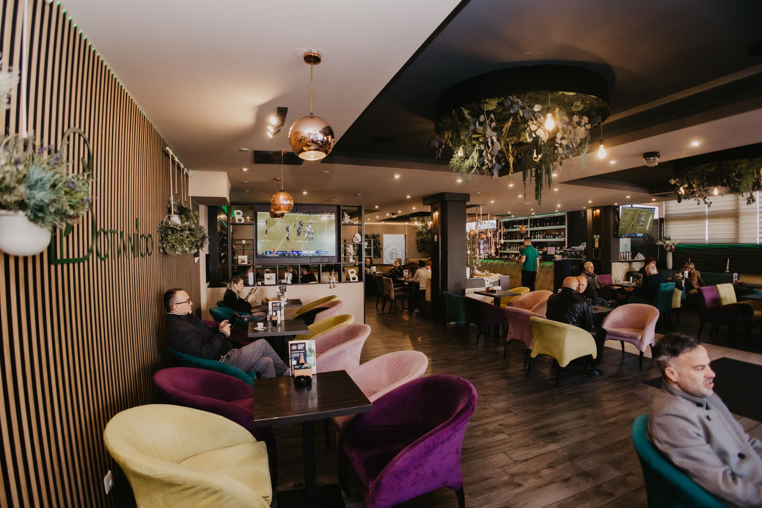 Modern restaurant interior with purple velvet chairs and wood accent walls.